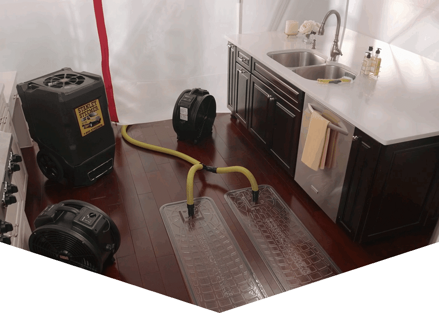 Stanley Steemer water extraction and drying equipment removing moisture from hardwood kitchen floor after a leak.